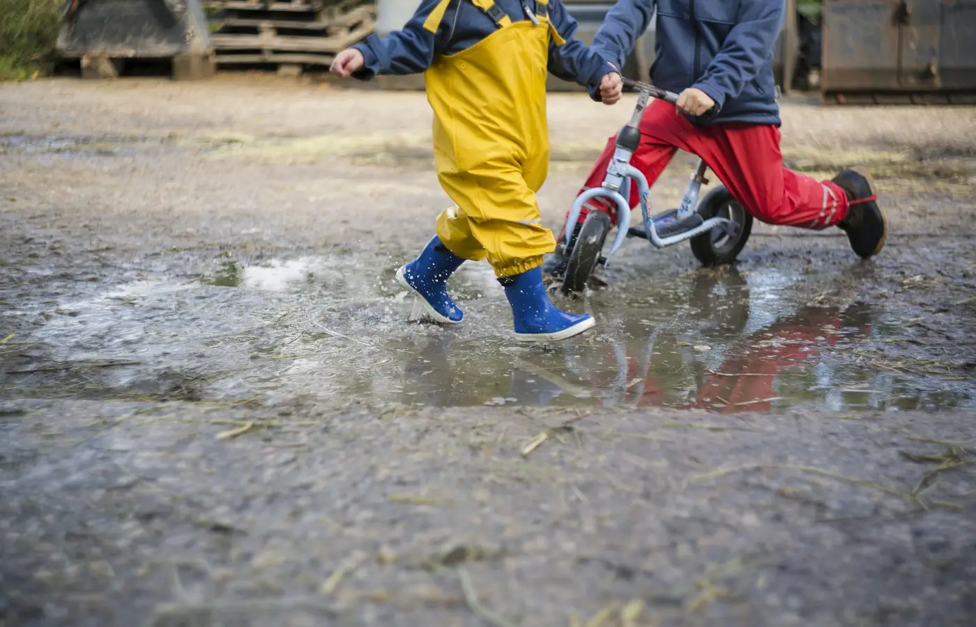 Child playing in a puddle in rain boots